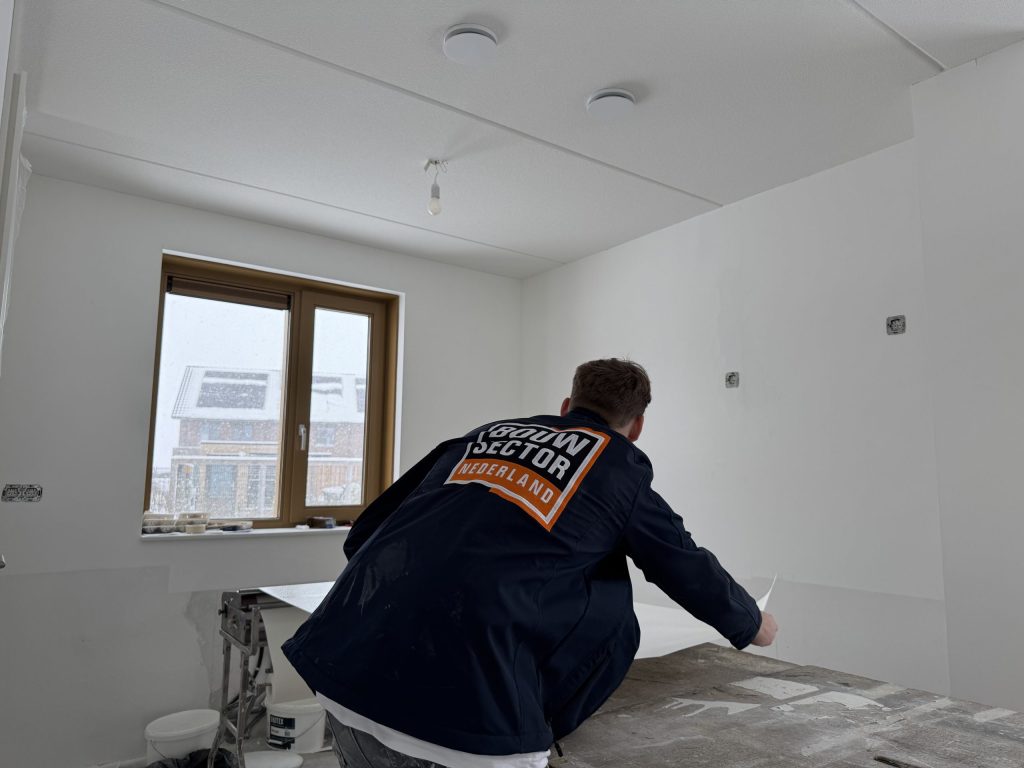 Behanger in een jas van Bouwsector Nederland werkt een baan af op de plaktafel