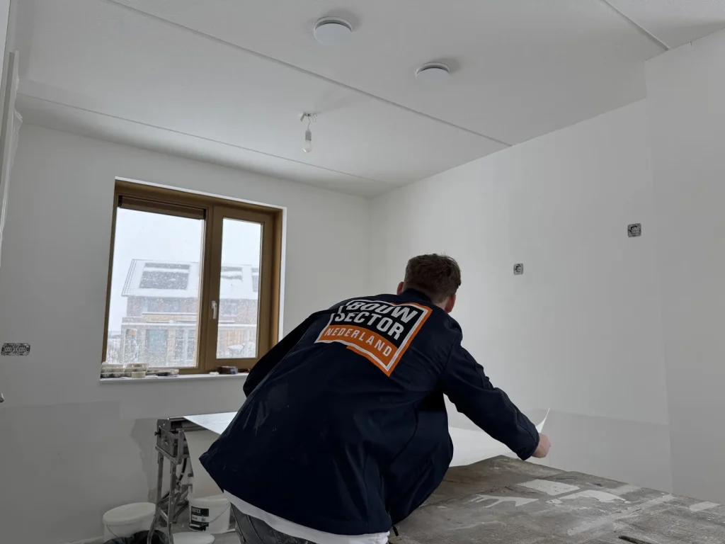 Behanger van Bouwsector Nederland snijdt een baan vlies op de plaktafel in een nieuwbouwkamer