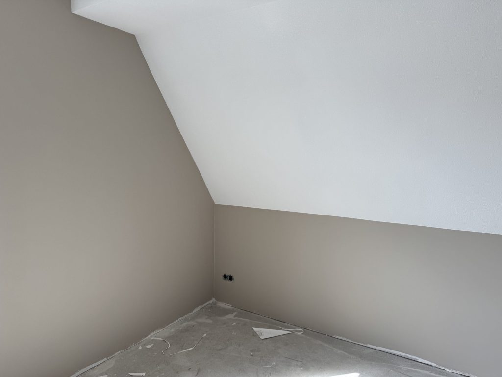 Zolderkamer met schuine wand en strak gesausde muren in twee kleuren